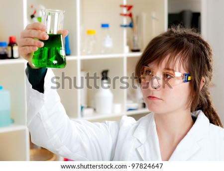 Young scientist mixes green liquid in a conical flask