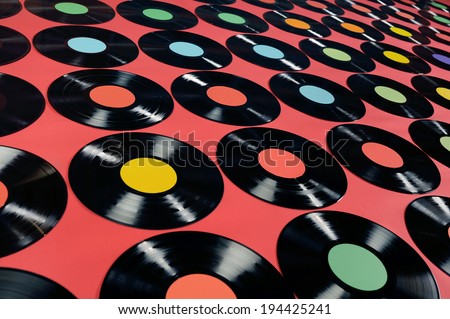 Music - Vinyl records. Colorful collection of vinyl records, LPs, on red background, angle view. The labels can be easily customized, the image is suitable for background use.