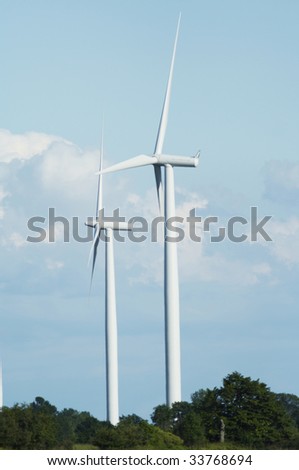 Two windmills stand against a blue cloudy sky.