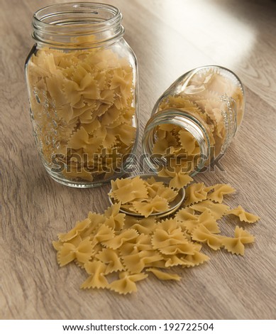 Pasta in the shape of a butterfly in a glass jar on the table