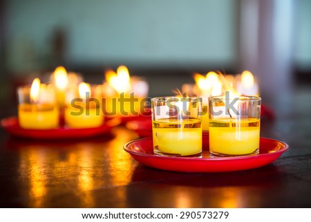Yellow candle in glass catch fire and red plate on wooden table