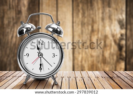 Modern silver metallic alarm clock on wooden table in vintage style