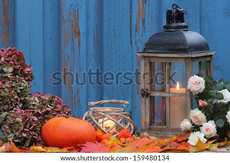 Pumpkin, storm lamp and lantern with white roses