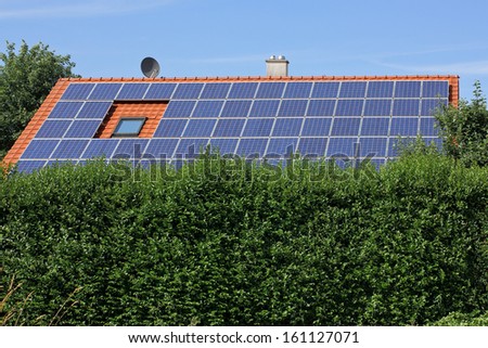 House with solar moduls with a hedge