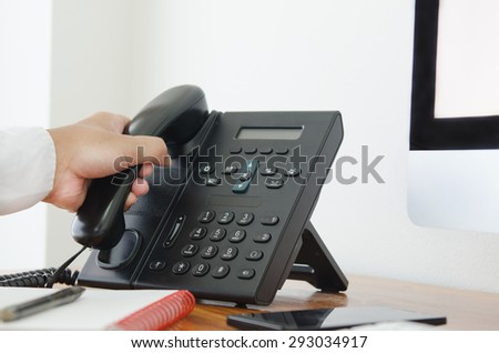 hand hold a telephone in the office for contact customer support