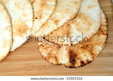 Six middle eastern flat bread disks stacked on top of each other.