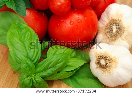 Fresh herbs and vegetables to make spaghetti sauce, including tomatoes, basil, oregano and garlic.
