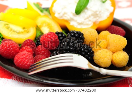 lo-cal salad made with red and golden raspberries, blackberries, yellow heirloom tomatoes with an orange bell pepper filled with cottage cheese topped with fresh basil