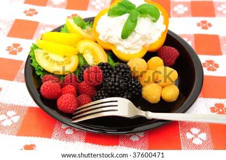 lo-cal salad made with red and golden raspberries, blackberries, yellow heirloom tomatoes with an orange bell pepper filled with cottage cheese topped with fresh basil