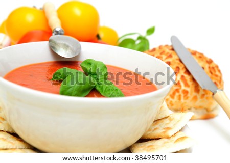 Bowl of tomato soup with crackers and a roll with  fresh tomatoes isolated on a white background
