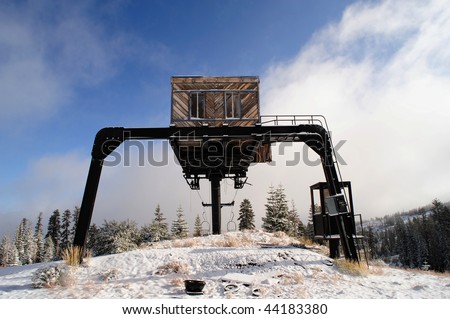 An old abandoned ski lift at the top of a mountain in the California Sierra Nevada mountains with a light covering of new snow