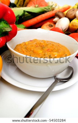 A bowl of warm creamy vegetable soup great for a cold winter day or a light meal with an assortment of fresh veggies in the background
