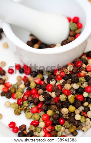 Peppercorns in various colors of red, green and the familiar black peppercorn on white with a Mortar and Pestle