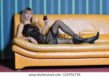 The blonde with a wine glass lays on sofa