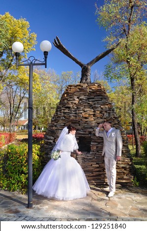 The groom looks at the bride and thinks near a monument to eagle