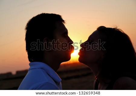 The guy and the girl kiss. The sun between them
