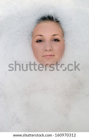 A girl takes a bath in the foam. Foam can see the face