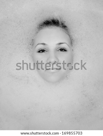 A girl takes a bath in the foam. Foam can see the face