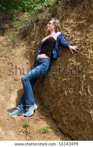 The girl has leant the elbows on a clay wall and looks afar