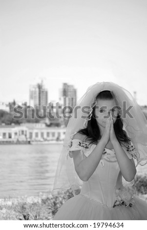 The bride against the river and a city, looks in the cam and nervous