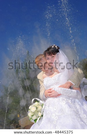 The groom embraces the bride. All is in the fountain splashes