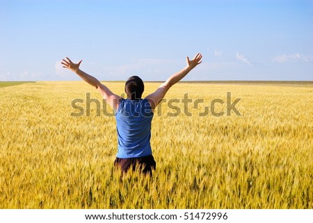 The man stands a back in an autumn field. Has lifted hands upwards