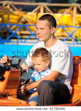 The father and the son go for a drive on the toy car