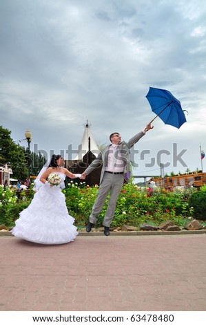 The groom departs on an umbrella. The bride holds the groom