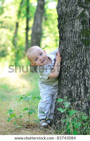 Boy playing hide and seek. Peeks out from behind a tree
