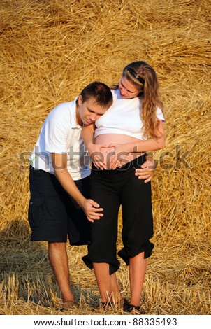 The guy embraces the pregnant girl and listens to a stomach