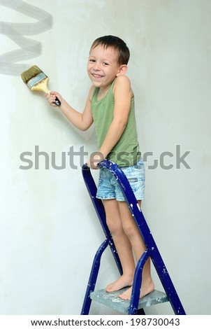 A boy stands on a ladder and does wallpaper paste on the wall