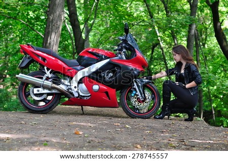 Girl sits near a motorcycle in the woods