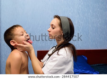 A doctor examines a child. The child shows tongue