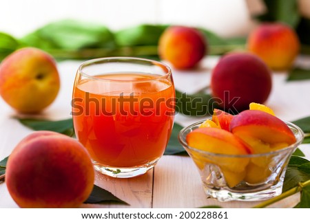Glass of peach smoothie with whole and sliced peaches