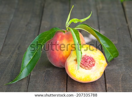 Peach and half of peach on wooden table