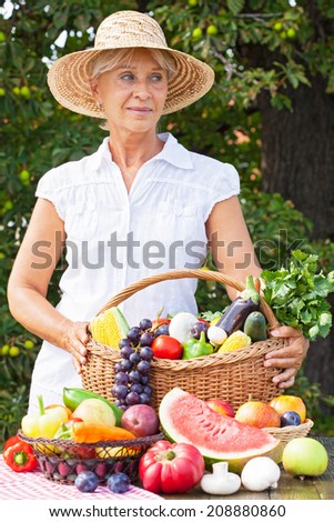 Woman with hat holding basket full of fruits and vegetables