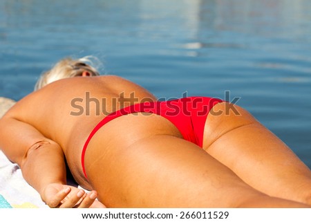 Adult woman sun tanning, near the sea