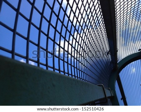 View through a enclosed train overpass walkway into the cloudy blue skies.