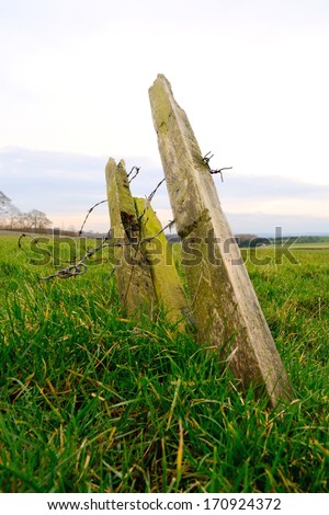 Old wooden fence post in rural field near Rightington, England.