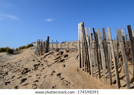 Old wooden fence leading to the sea at Formby Beach, England.
