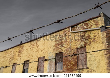 The barbed wire with old brick building in background.