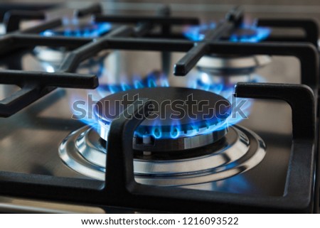 Stainless steel kitchen surface with cast-iron grill. Burning gas burners.
