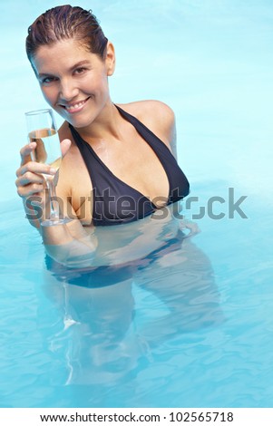 Happy woman drinking glass of sparkling wine in swimming pool