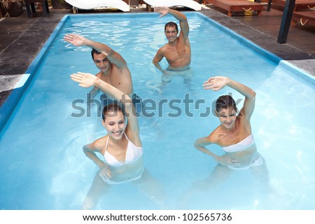 Smiling group doing aqua aerobics in swimming pool