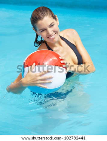 Happy attractive woman with beach ball in swimming pool