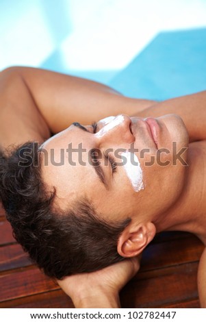Relaxed man sunbathing with sunscreen on his nose and cheeks