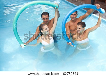 Group in swimming pool doing water aerobics with swim noodles