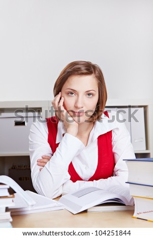 Portrait of attractive woman with many books at her desk
