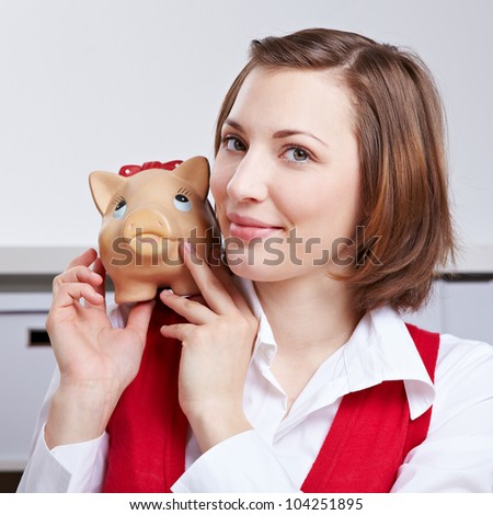 Successful business woman with piggy bank on shoulder sitting in office