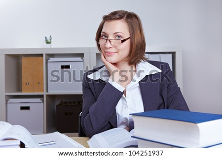 Smiling female business consultant with many books in the office